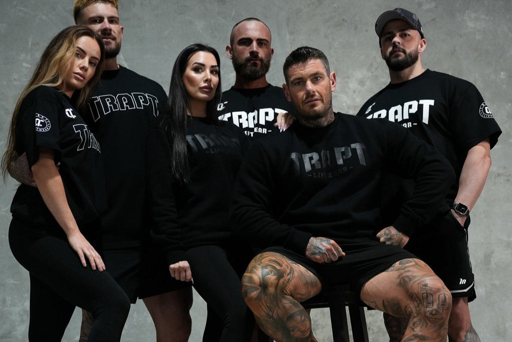 Group of people wearing black 'TRAPT' t-shirts against a gray background